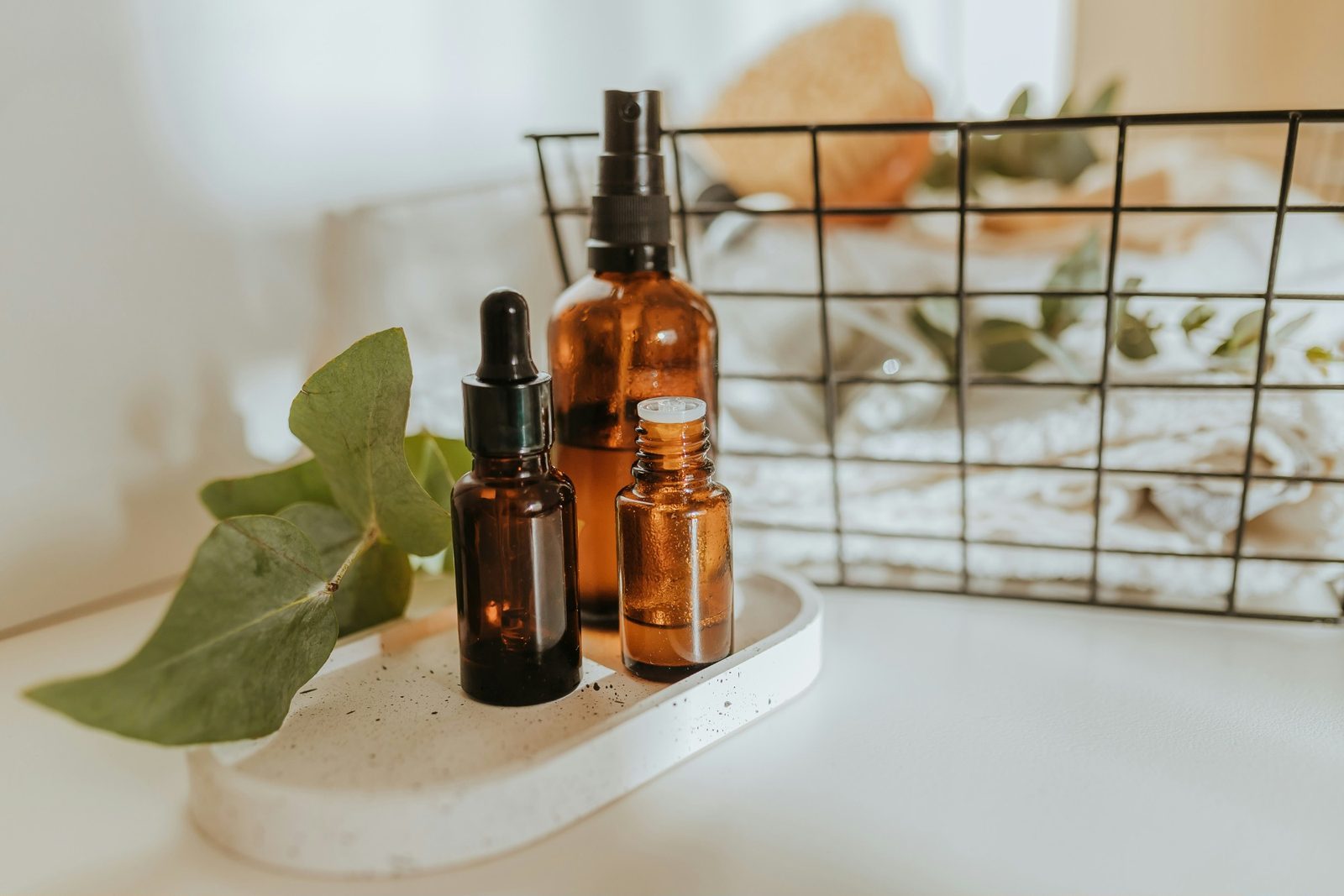 Amber dropper bottles on a stone tray beside eucalyptus leaves
